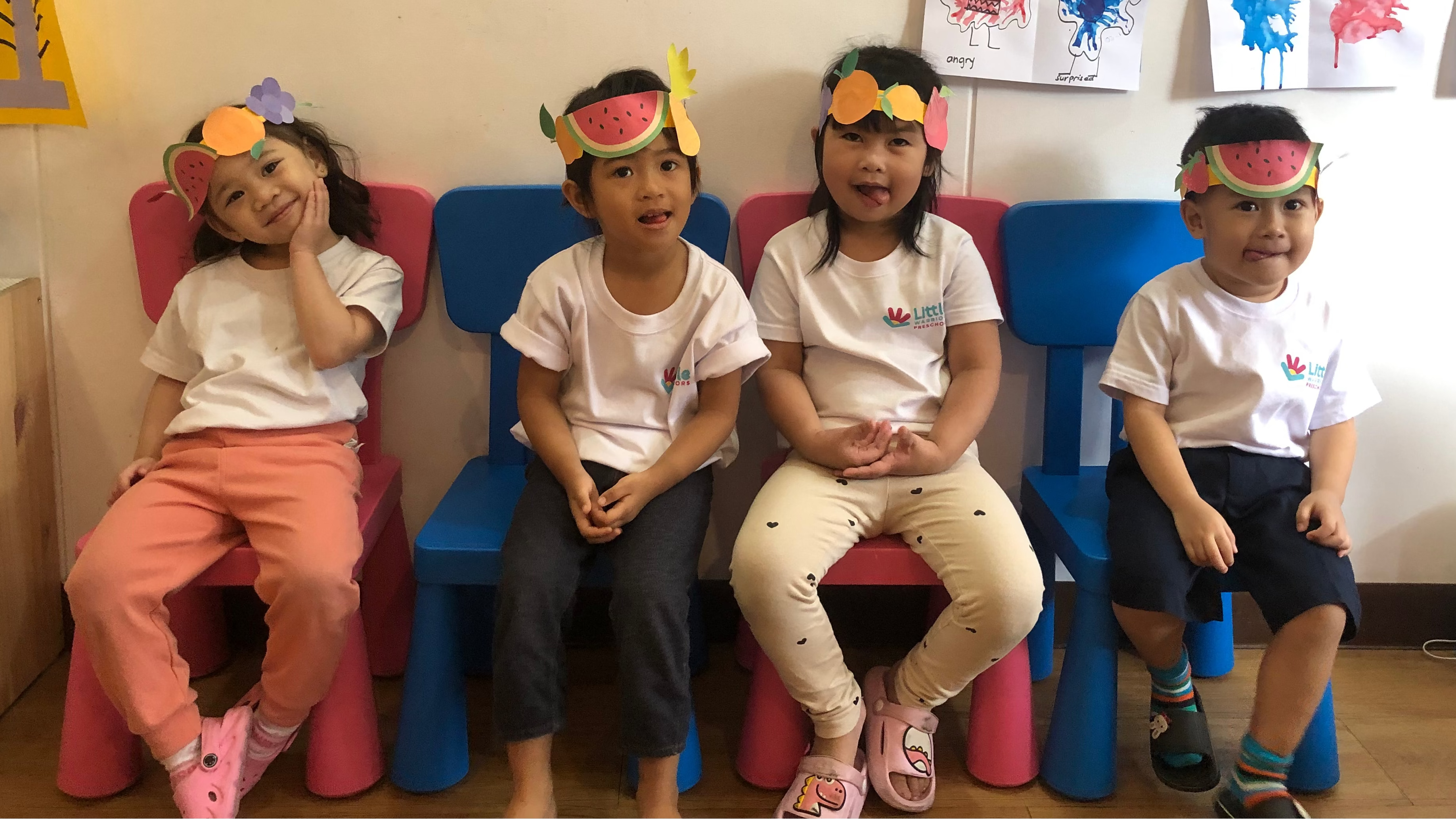 Children / Toddler Students of Little Warriors Preschool wearing arts & crafts hat do a wacky pose in the classroom in celebration of Nutrition Month.